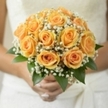 Radiating joy and the ambient glow of an early Sands End sunrise, this bridal bouquet is a celebration of warmth and optimism. Spirals of soft peach roses, each petal tinged with golden light, are gathered together with precision and care, forming a lush, rounded display. Delicate sprays of baby's breath weave between the roses, their tiny white blossoms casting a gentle haze that adds softness and an almost dreamlike romance to the ensemble. Glossy, fresh leaves at the base provide a crisp green frame, their natural simplicity grounding the arrangement in the vibrant energy of local community gardens. The bouquet appears to glow in natural daylight, echoing the hopefulness and excitement of a wedding morning near Hurlingham Park. Its sweet, understated fragrance lingers, promising cherished memories and laughter on a day of celebration. As a florist in Sands End, there is a true joy in blending tradition and vibrancy-each thoughtful detail, from the perfect opening of every rose to the misty veil of gypsophila, marks this bouquet as an ideal companion for brides embarking on lifelong journeys, surrounded by the beauty and heart of their neighbourhood.
